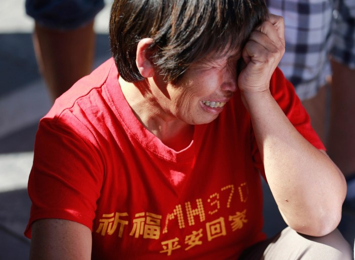 Image: A family member of passengers onboard the missing Malaysia Airlines Flight MH370 cry as they gather to pray Yonghegong Lama Temple in Beijing
