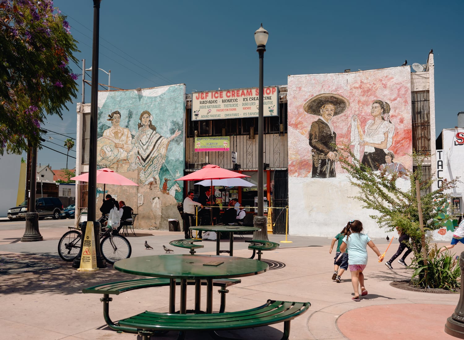 Children play by an ice cream shop surrounded by murals in Boyle Heights.