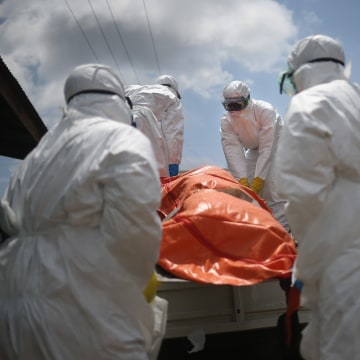 Image: An Ebola burial team loads the body of a woman, 54, onto a truck for cremation