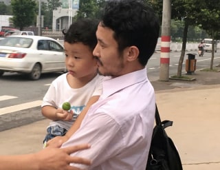Image: Activist Hua Haifeng carries his son Bobo as they leave a police station in Ganzhou, China.