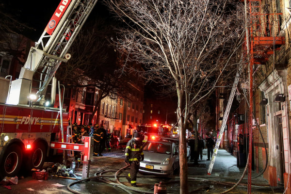 Image: Fire Department of New York (FDNY) personnel work on the scene of an apartment fire in New York