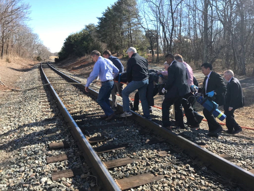 Image: One of the injured is carried across train tracks to an ambulance after a train carrying members of Congress collided with a garbage truck in Crozet, Virginia