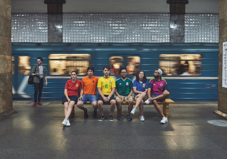 Image: Gay rights activists, wearing soccer jerseys to form a rainbow flag, sit on a bench in the metro in Moscow