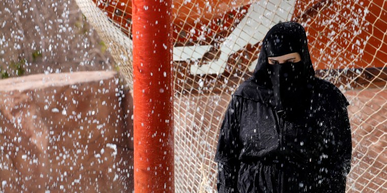 Image: A woman wearing a full veil (niqab) uses a shower to cool off in hot and humid weather inside an Aqua arena during summer holidays at El Ain El Sokhna in Suez, east of Cairo