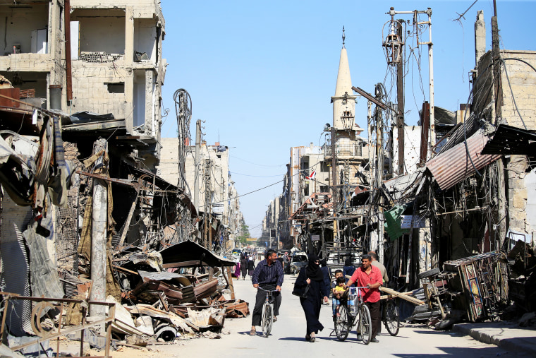 People walk in a street during a media tour in Douma near Damascus