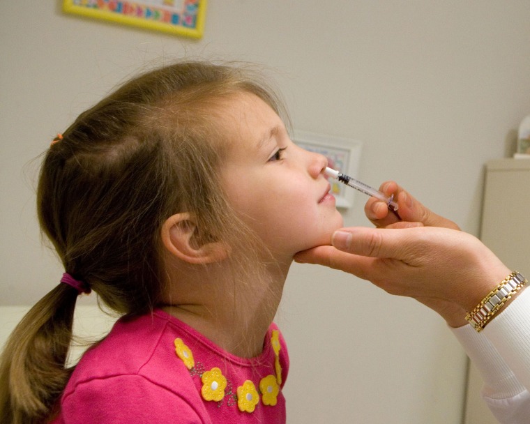Image: A healthcare provider uses an empty sample sprayer to demonstrate how to administer FluMist to a preschooler.