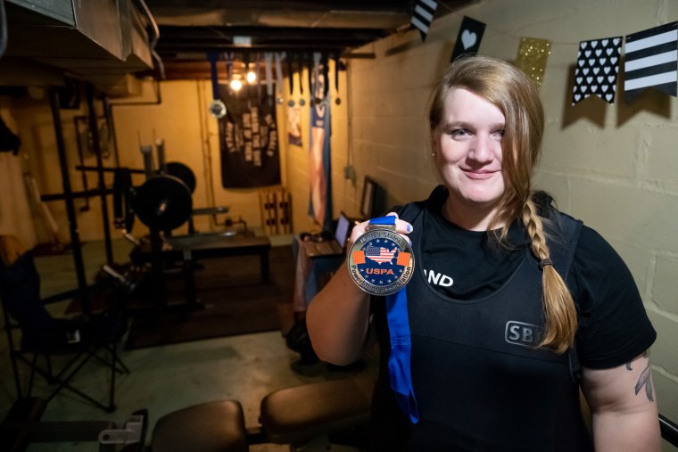 Photograph of JayCee Cooper holding a lifting medal.