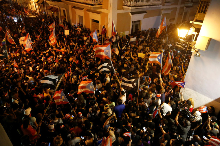 Image: Demonstrators chant slogans as they wave Puerto Rican flags during ongoing protests calling for the resignation of Governor Ricardo Rossello in San Juan
