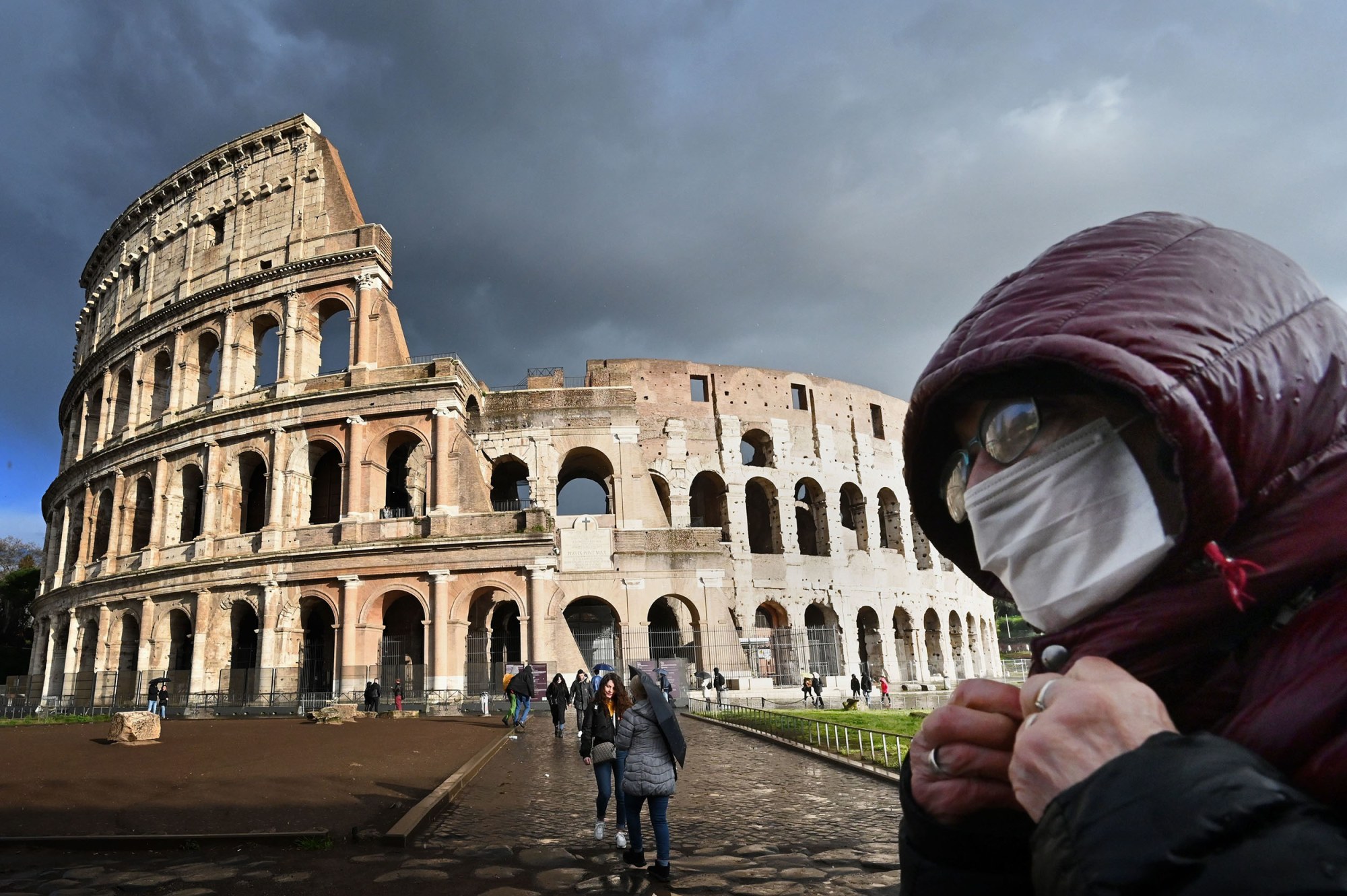 Image: A man wearing a protective mask passes by the Colosseum in Rome on March 7, 2020 amid fear of Covid-19 epidemic.