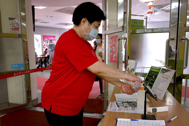 Image: A woman sanitizes her hands before going into a sports center in Taipei. Hand sanitizers are made available in many buildings and businesses in Taiwan.