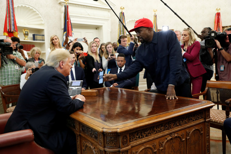 Rapper Kanye West shows President Trump his mobile phone during meeting in the Oval Office at the White House in Washington