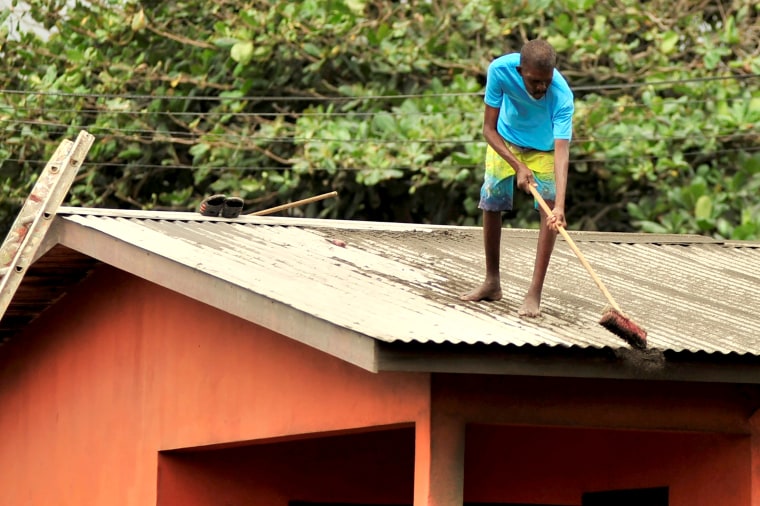 Image: Local residents clear ash from a roof after a series of eruptions from La Soufriere volcano