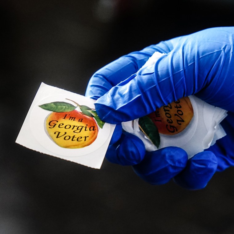 A polling place worker holds an "I'm a Georgia Voter" sticker to hand to a voter on June 9, 2020 in Atlanta.